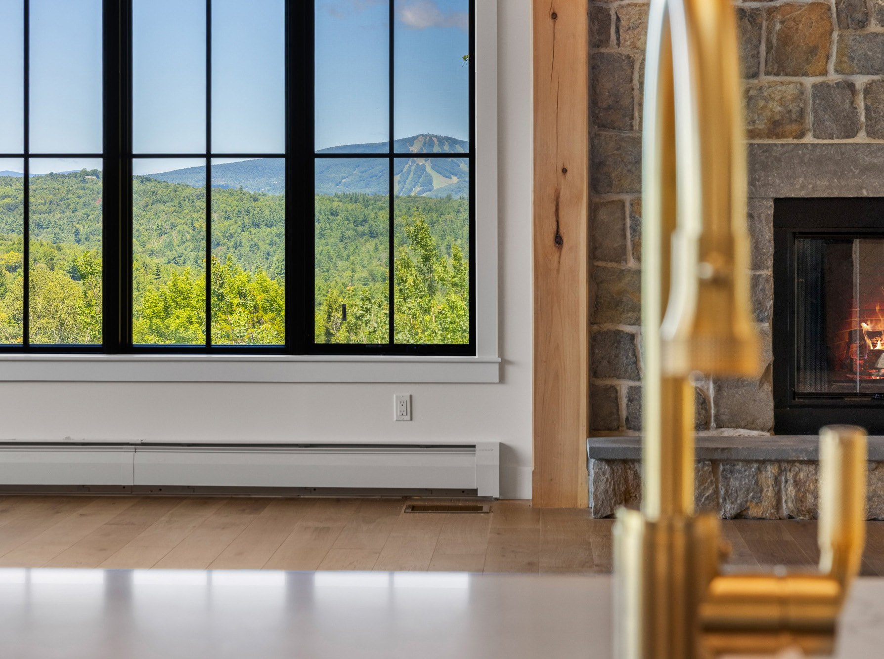 Great room windows framing Green Mountain views beside the stone hearth