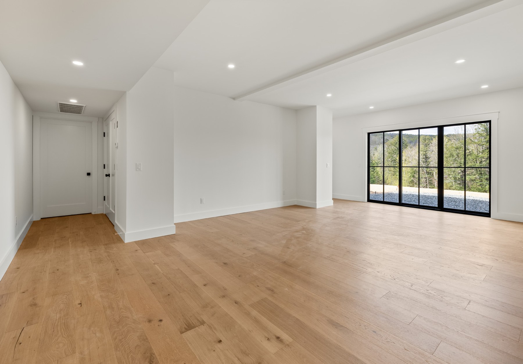 Spacious game room with light wood floors opening to the outdoors