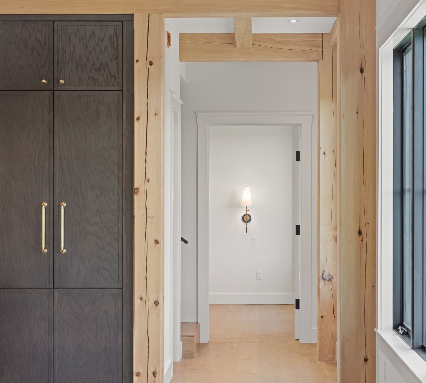 Hallway with dark cabinetry and natural wood trim