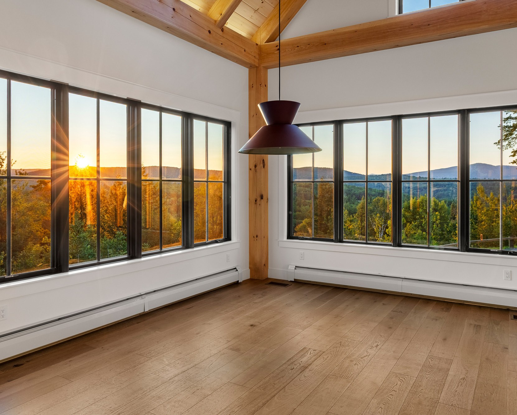 Room with large windows overlooking a mountain sunset