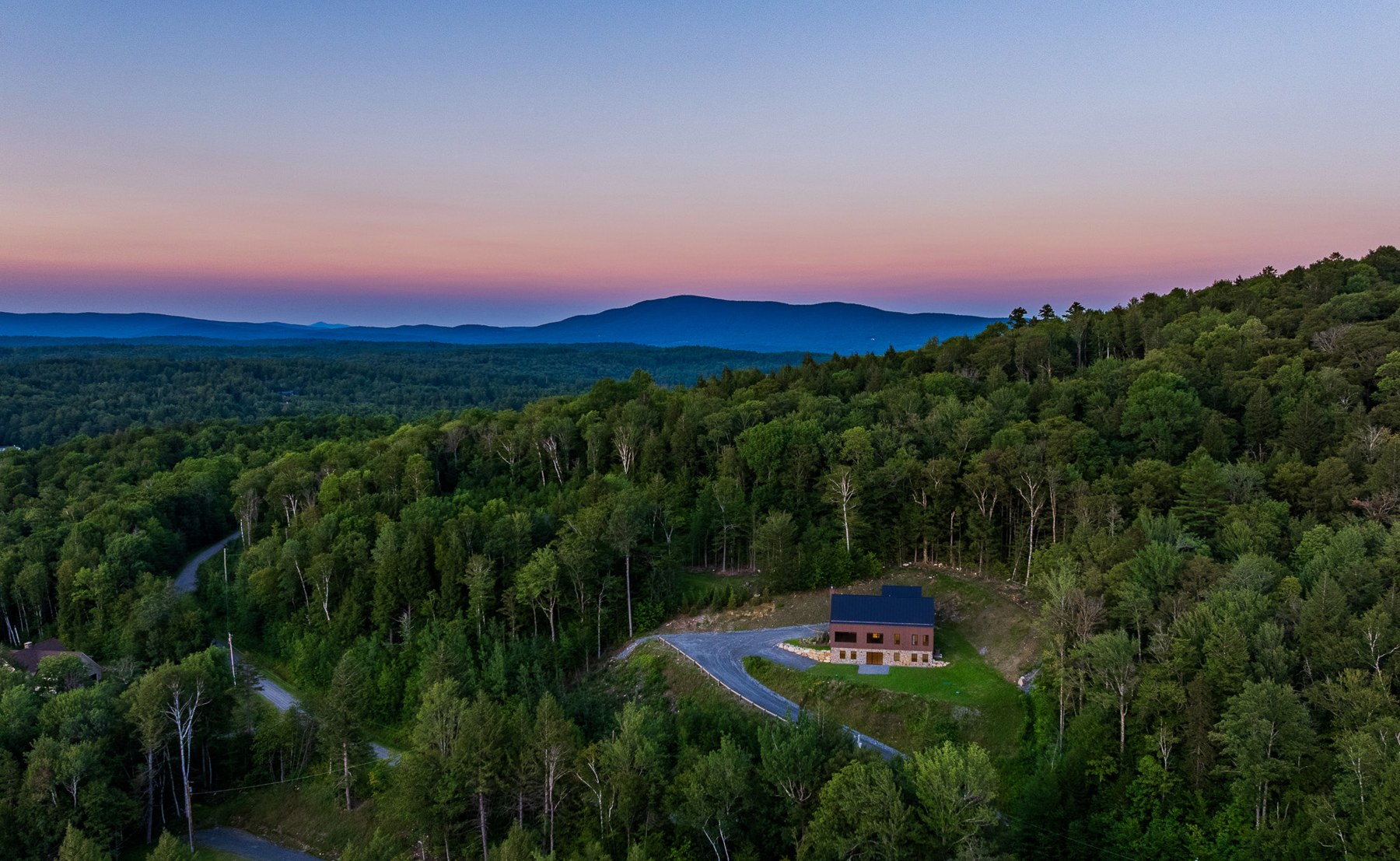 Aerial view of Stone Lodge set among Vermont evergreens at sunset